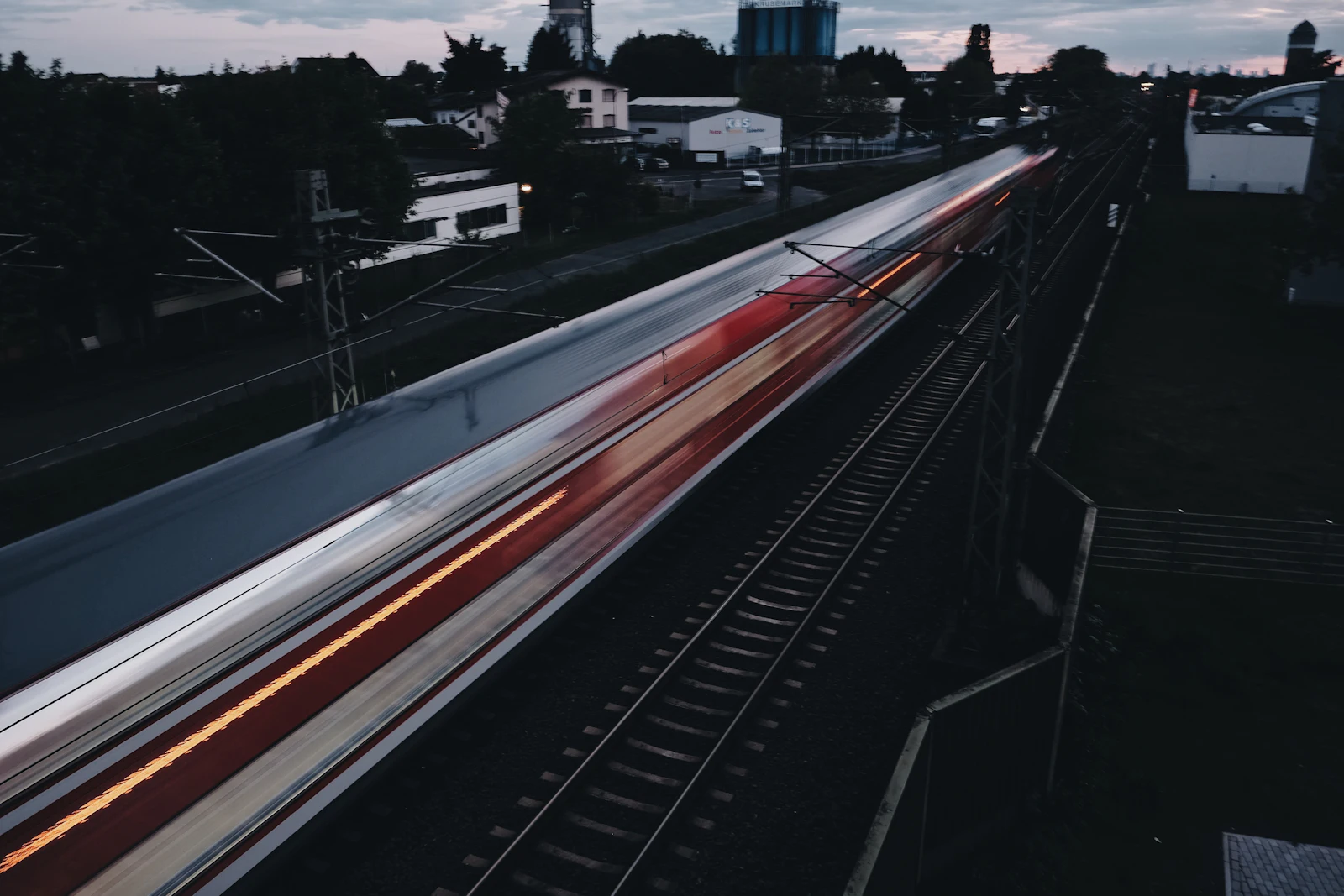 Passenger train in motion at dusk, light trails along the track