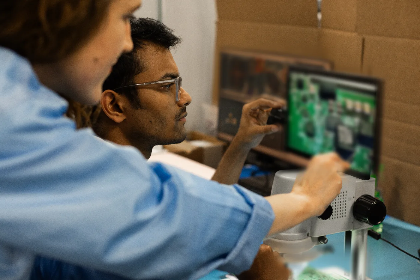 BSU engineer reviewing a board on a digital microscope with a colleague